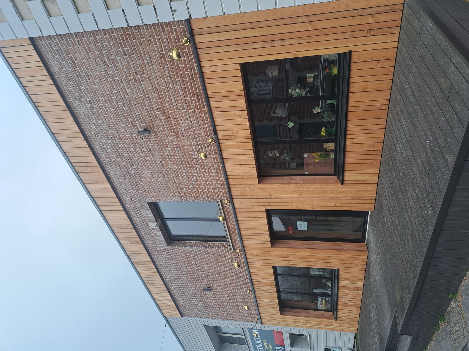 Façade commerciale rénovée : brique en partie haute et bardage bois clair en partie basse — réalisation Dagicour Envermeu