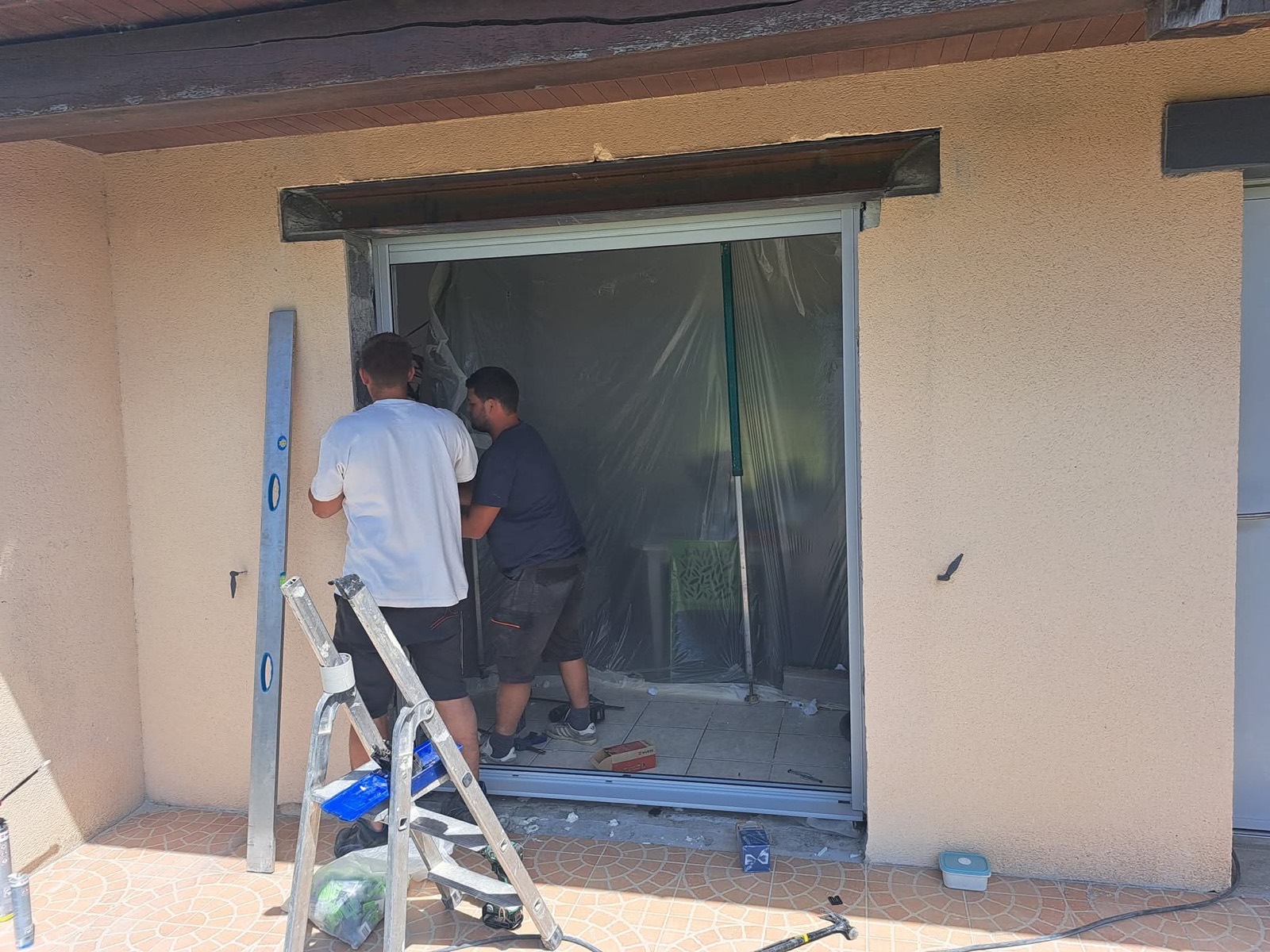 Poseurs Dagicour installant une baie coulissante aluminium sous film de protection sur une maison en Normandie