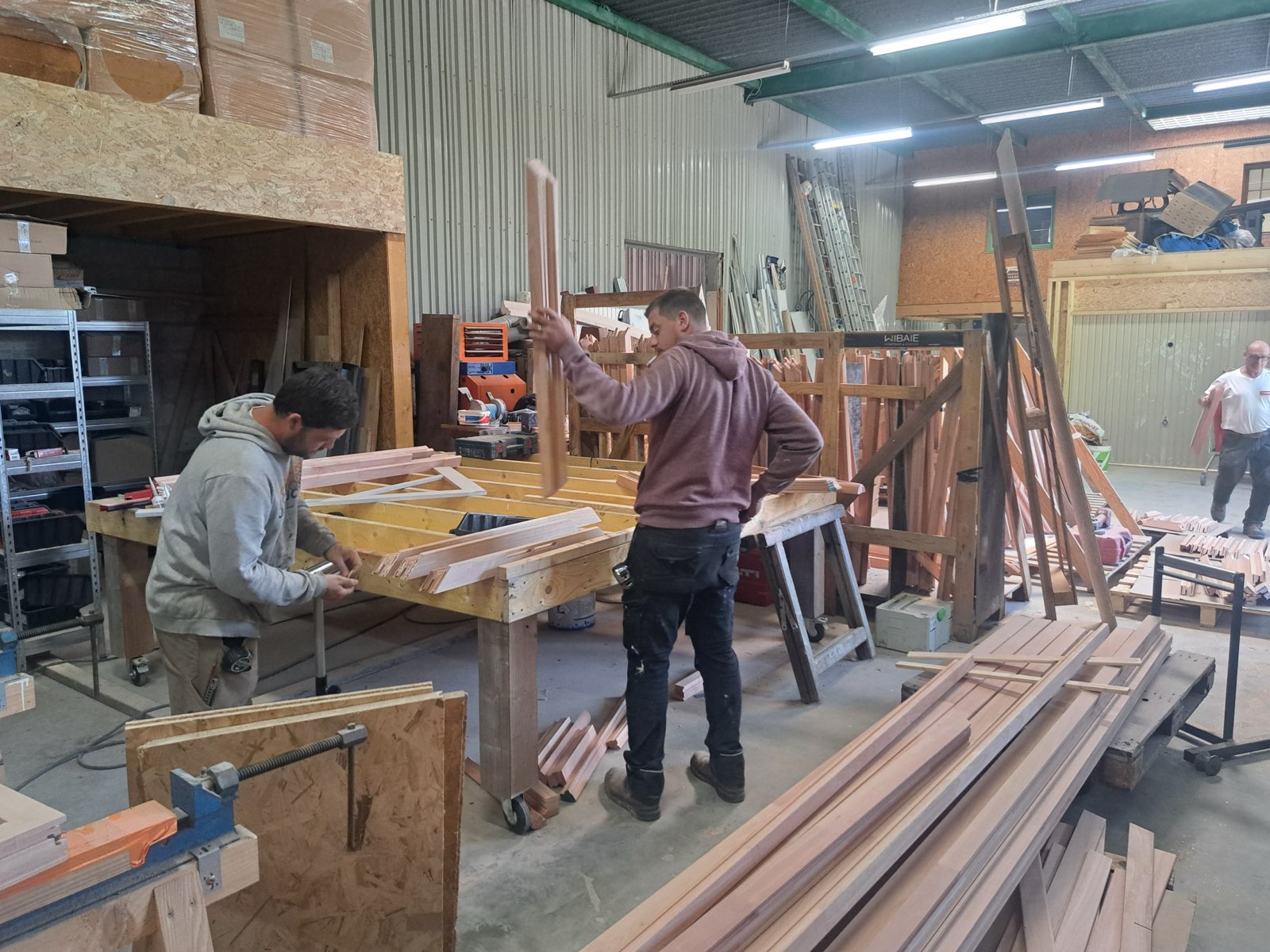 Menuisiers assemblant un dormant de fenêtre en bois massif sur établi — atelier Dagicour Envermeu