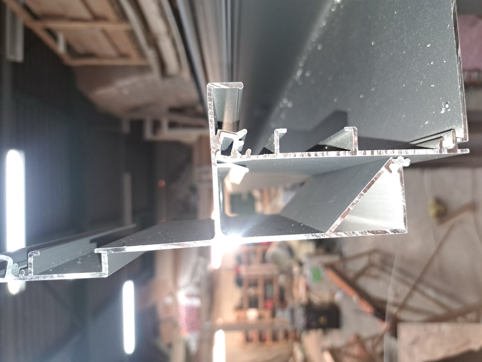 Menuisier Dagicour manipulant un profilé aluminium en atelier avant assemblage