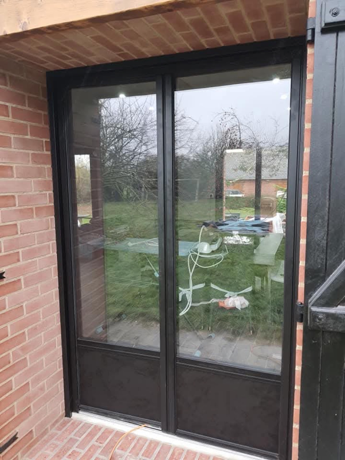 Baie vitrée coulissante aluminium noir à 2 vantaux sur façade en briques — Dagicour Normandie