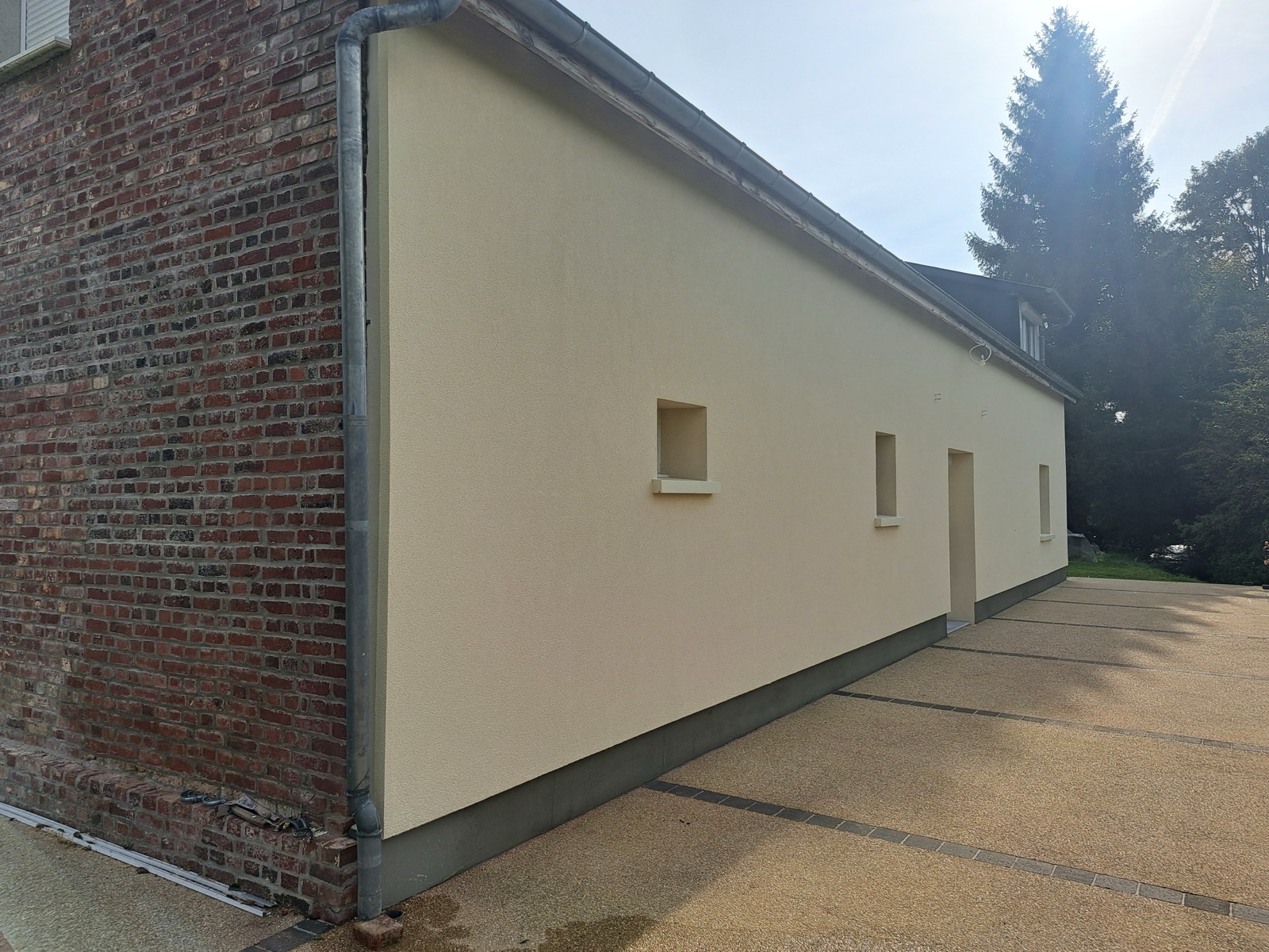 Angle de façade associant enduit ITE beige et brique apparente conservée — charme normand Dagicour