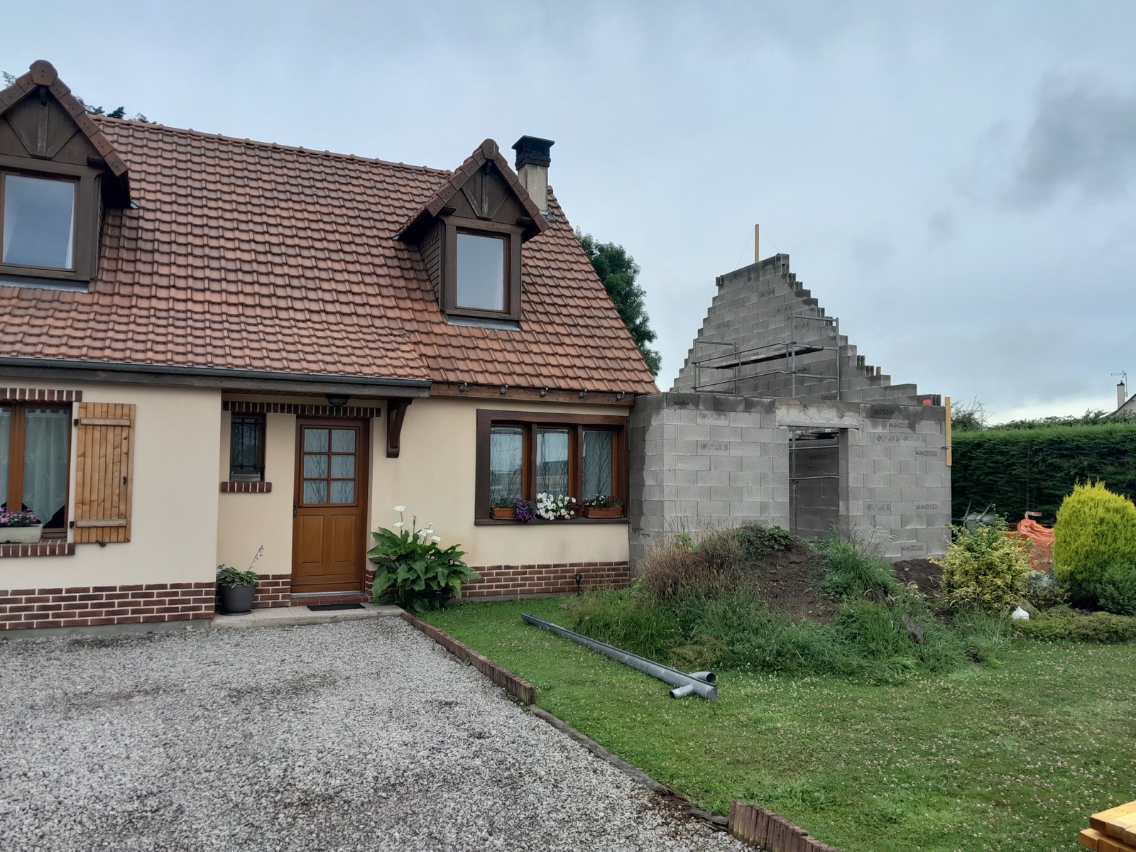 Extension en parpaings en cours de construction contre une maison normande traditionnelle — chantier Dagicour