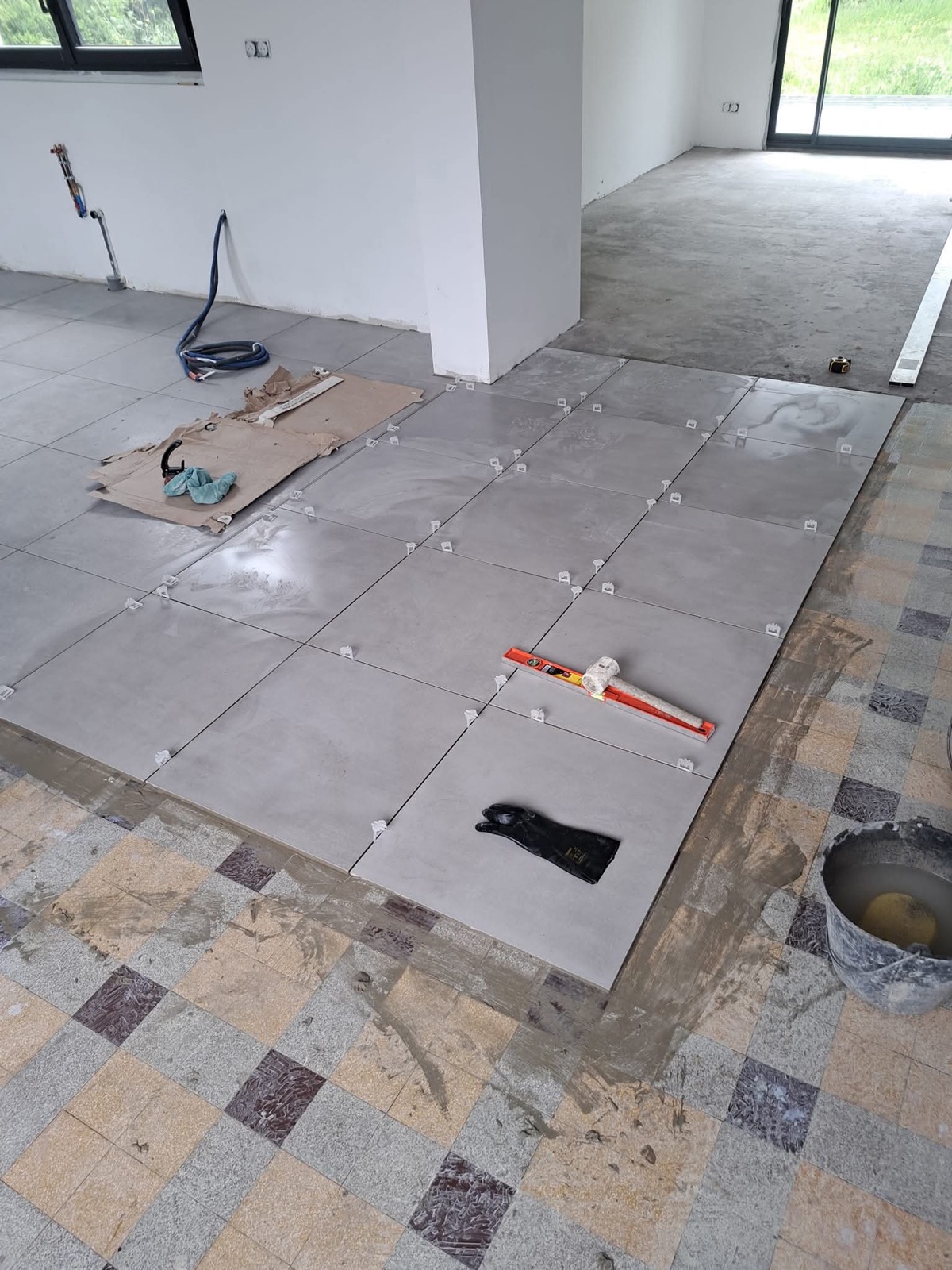 Carrelage grand format en cours de pose dans une pièce à vivre avec baie vitrée sur jardin — chantier Dagicour Seine-Maritime