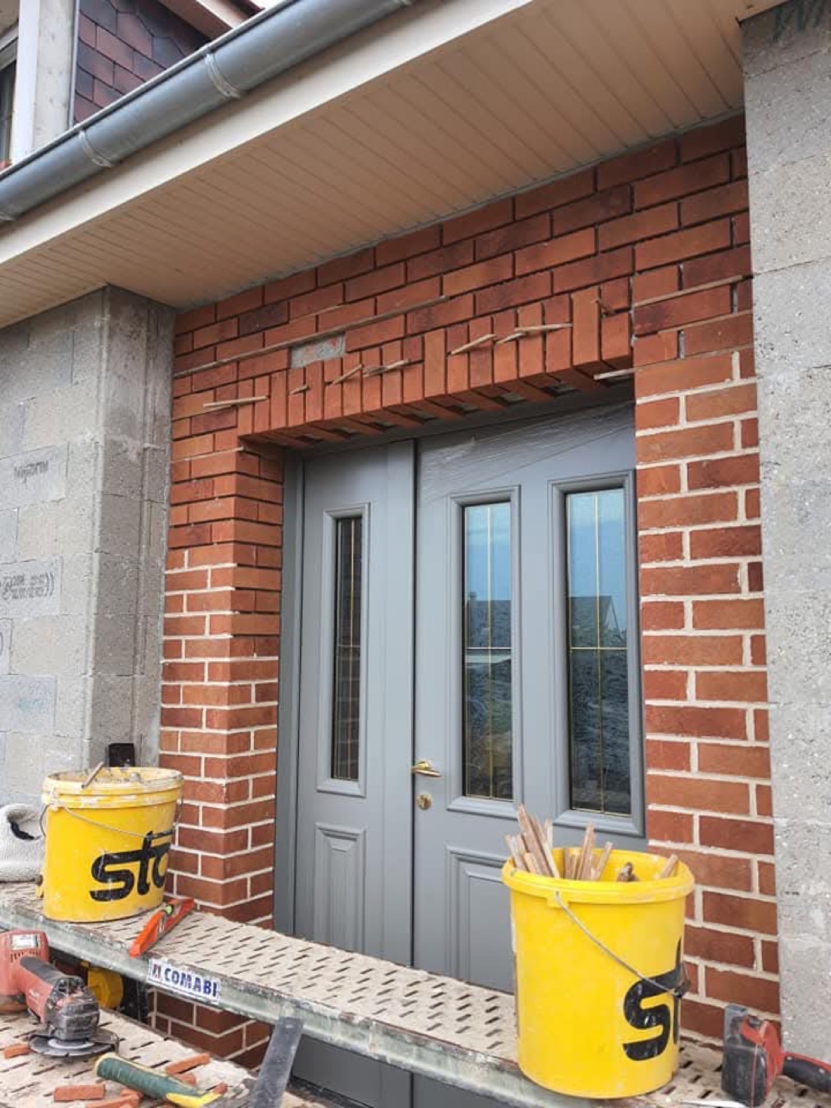 Encadrement en briques de parement autour d'une porte d'entrée grise, finition maçonnerie soignée — Dagicour