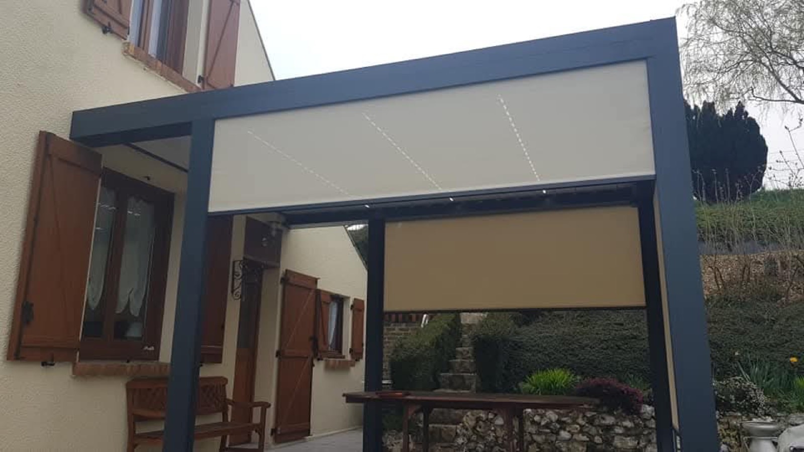 Pergola avec stores latéraux rétractables déployés, coin repas extérieur — Dagicour Normandie