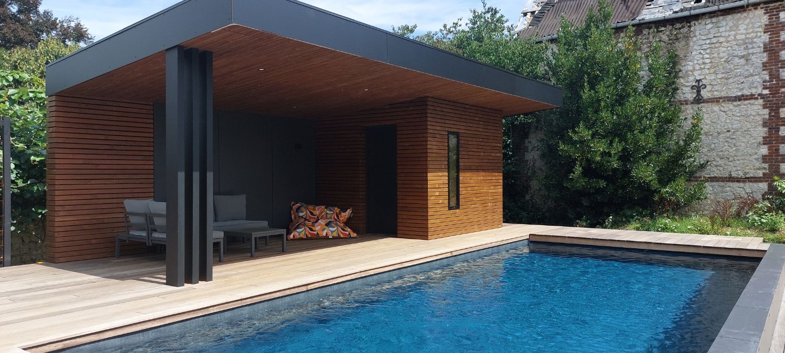 Pool house en bois avec toit casquette anthracite et terrasse en bois exotique au bord d'une piscine — Dagicour Normandie