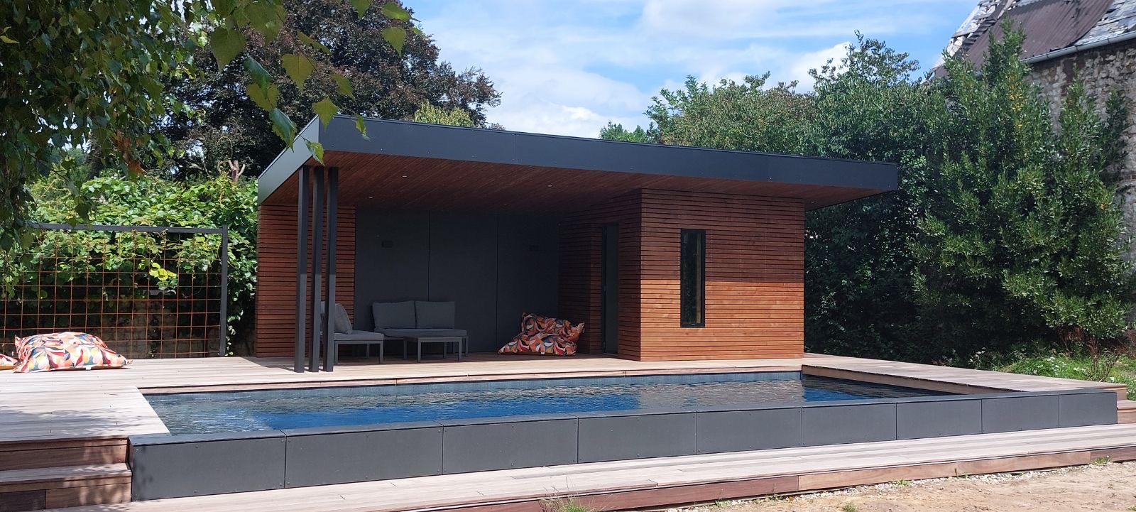 Pool house classique en bois avec assises intégrées, casquette de toit en surplomb sur piscine — Dagicour
