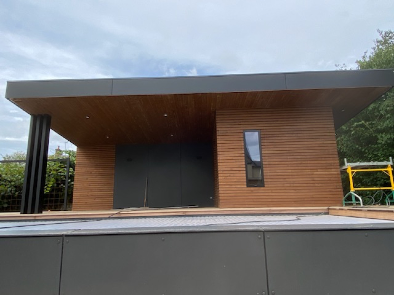 Studio de jardin fermé en bardage bois et panneaux anthracite, façade fermée — réalisation Dagicour