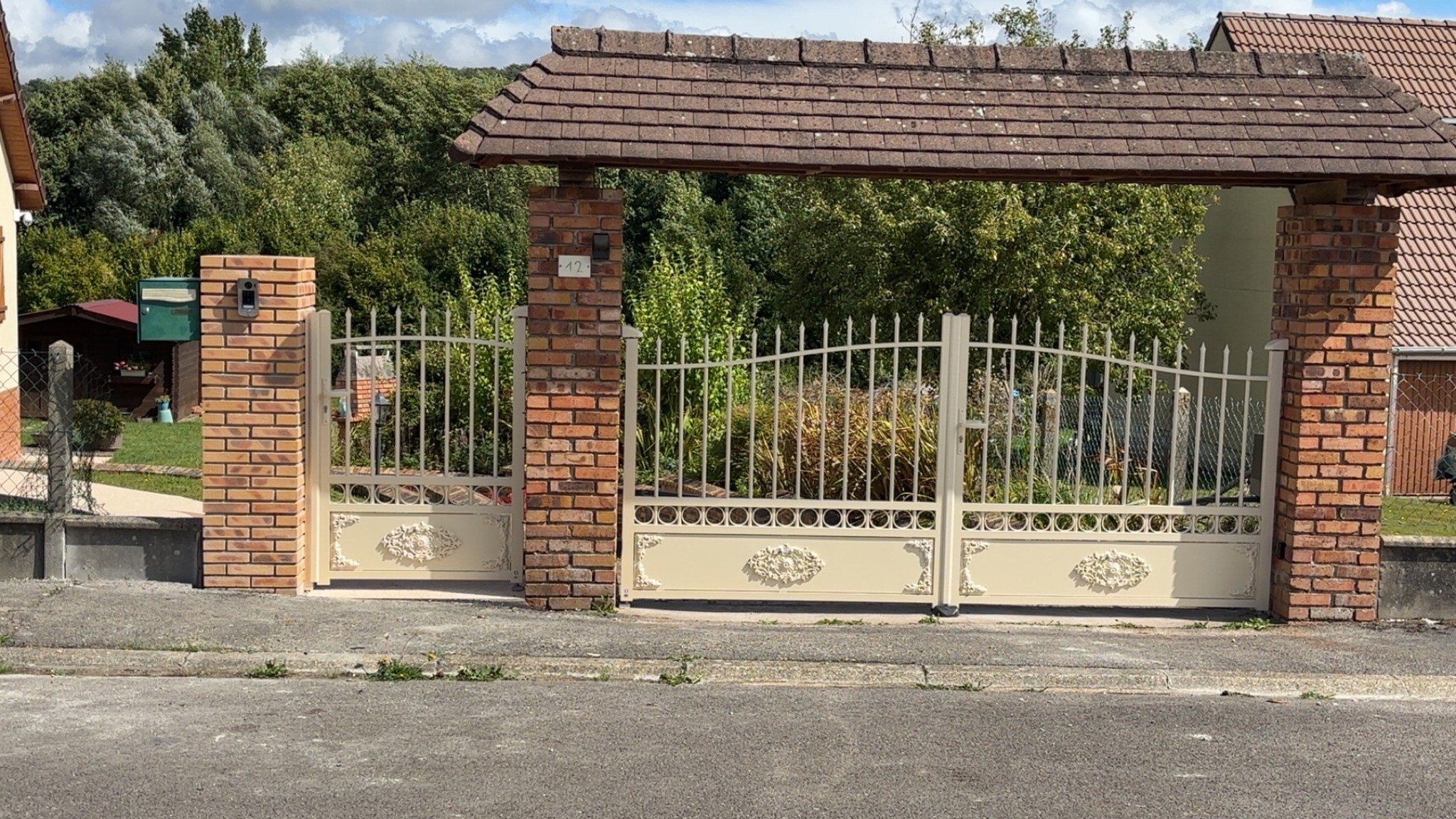 Portail décoratif blanc à barreaudage sous porche en briques, style classique — réalisation Dagicour
