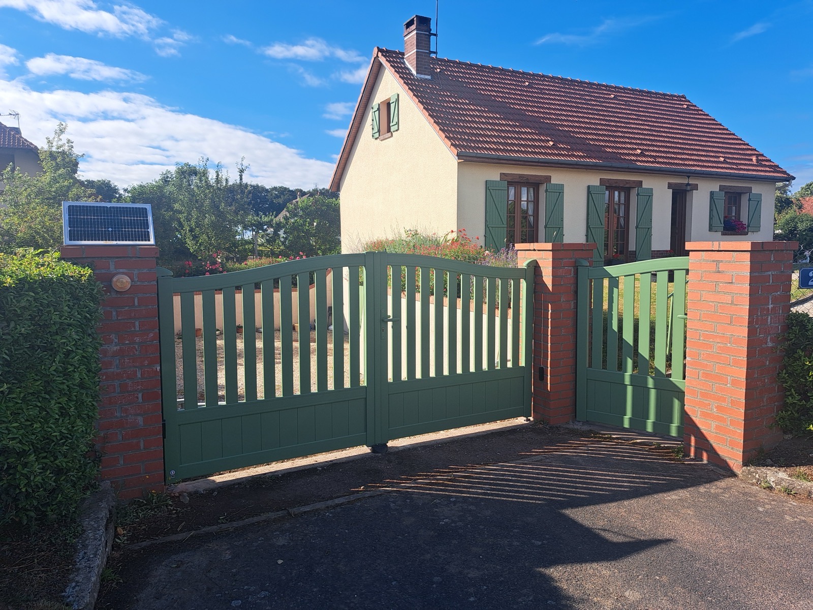 Portail aluminium imitation bois vert avec panneau solaire sur piliers briques — réalisation Dagicour