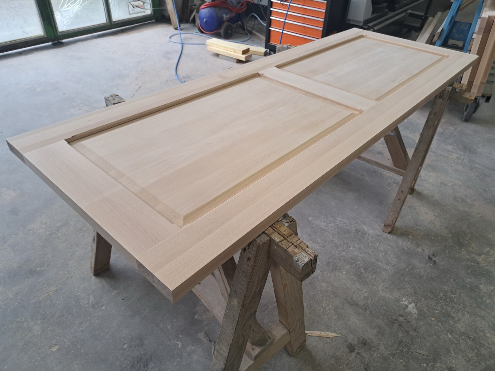 Porte d'entrée en bois massif à panneaux moulurés, fraîchement fabriquée en atelier — menuiserie Dagicour Envermeu