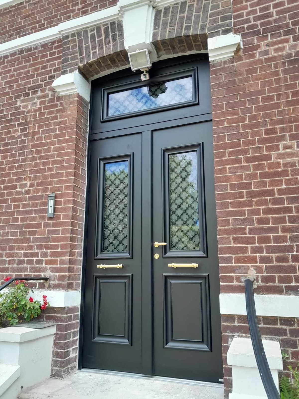 Porte d'entrée noire à 2 vantaux avec ferrures dorées sur façade en briques — Dagicour Normandie