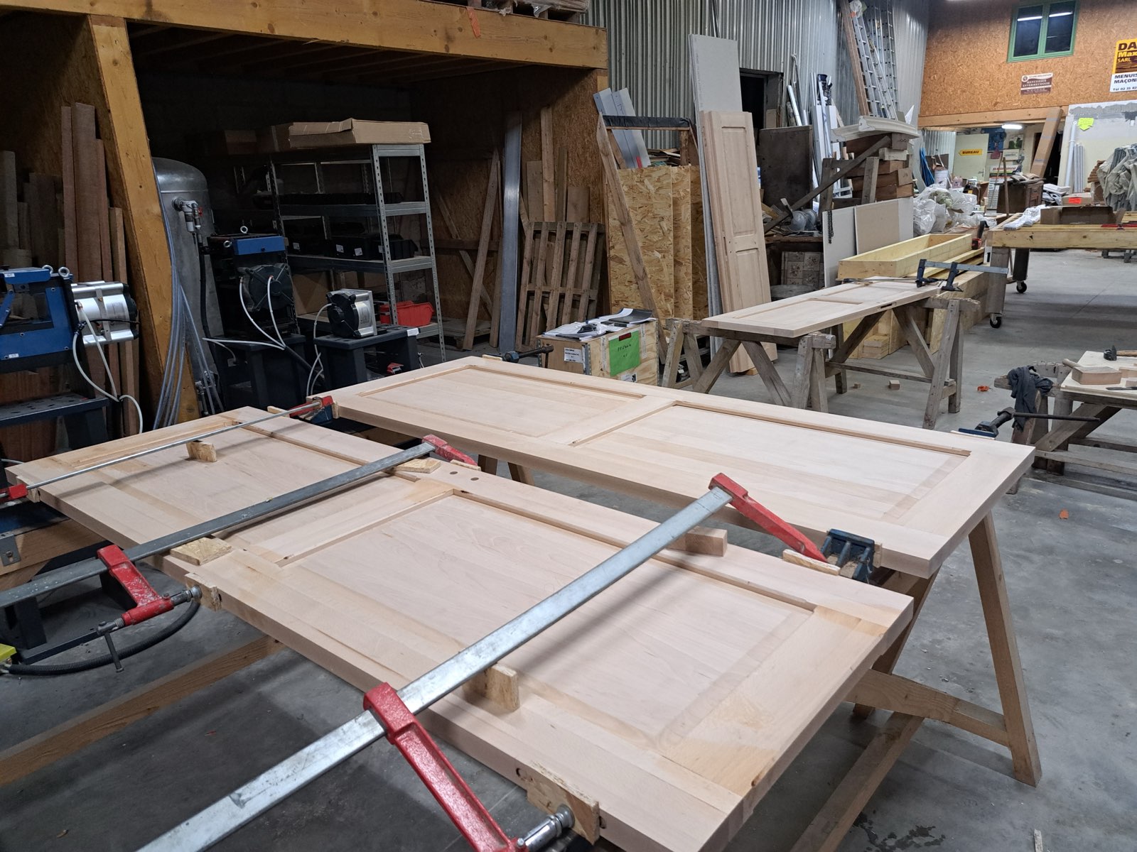 Vue large de l'atelier de menuiserie Dagicour avec plusieurs portes en cours de fabrication