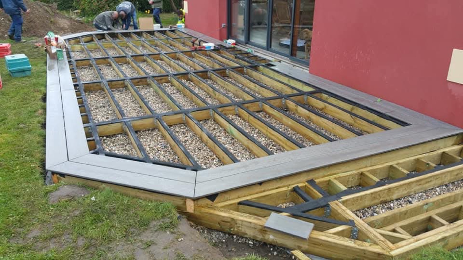 Ossature de terrasse sur plots noirs réglables en cours de montage — équipe Dagicour