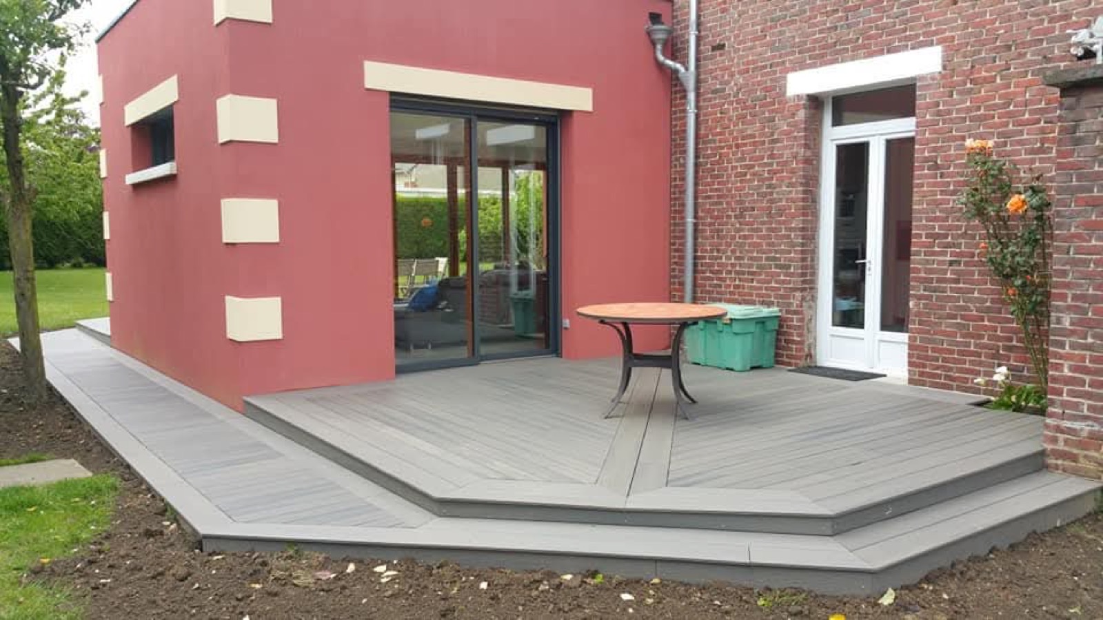 Après : terrasse composite grise octogonale avec table de jardin sur extension rouge — Dagicour