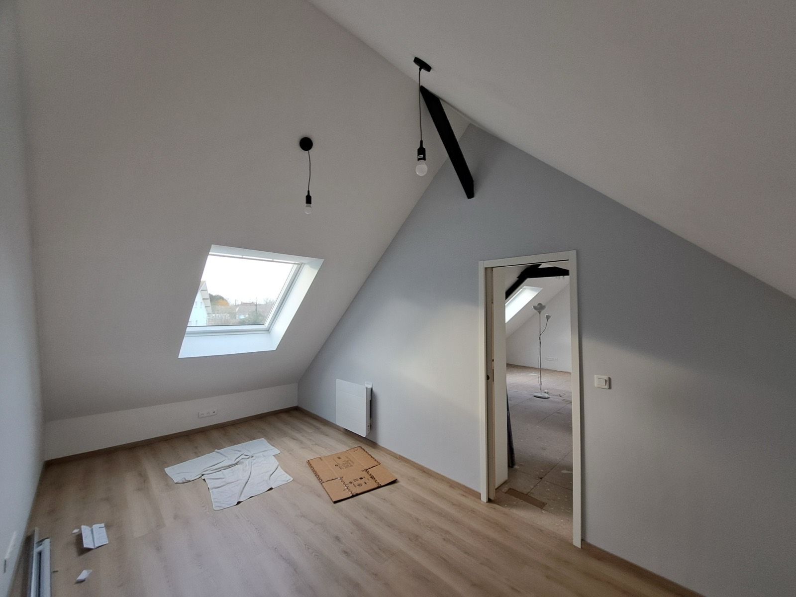 Après travaux : même pièce de combles finie, murs peints, parquet posé et velux, même chantier — Dagicour