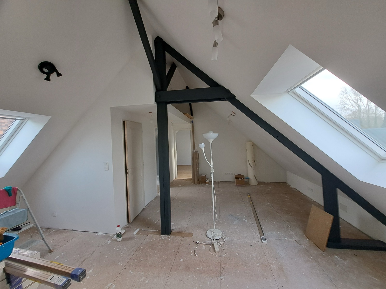 Grande pièce de combles aménagée avec poutre noire, deux velux et parquet clair, Seine-Maritime