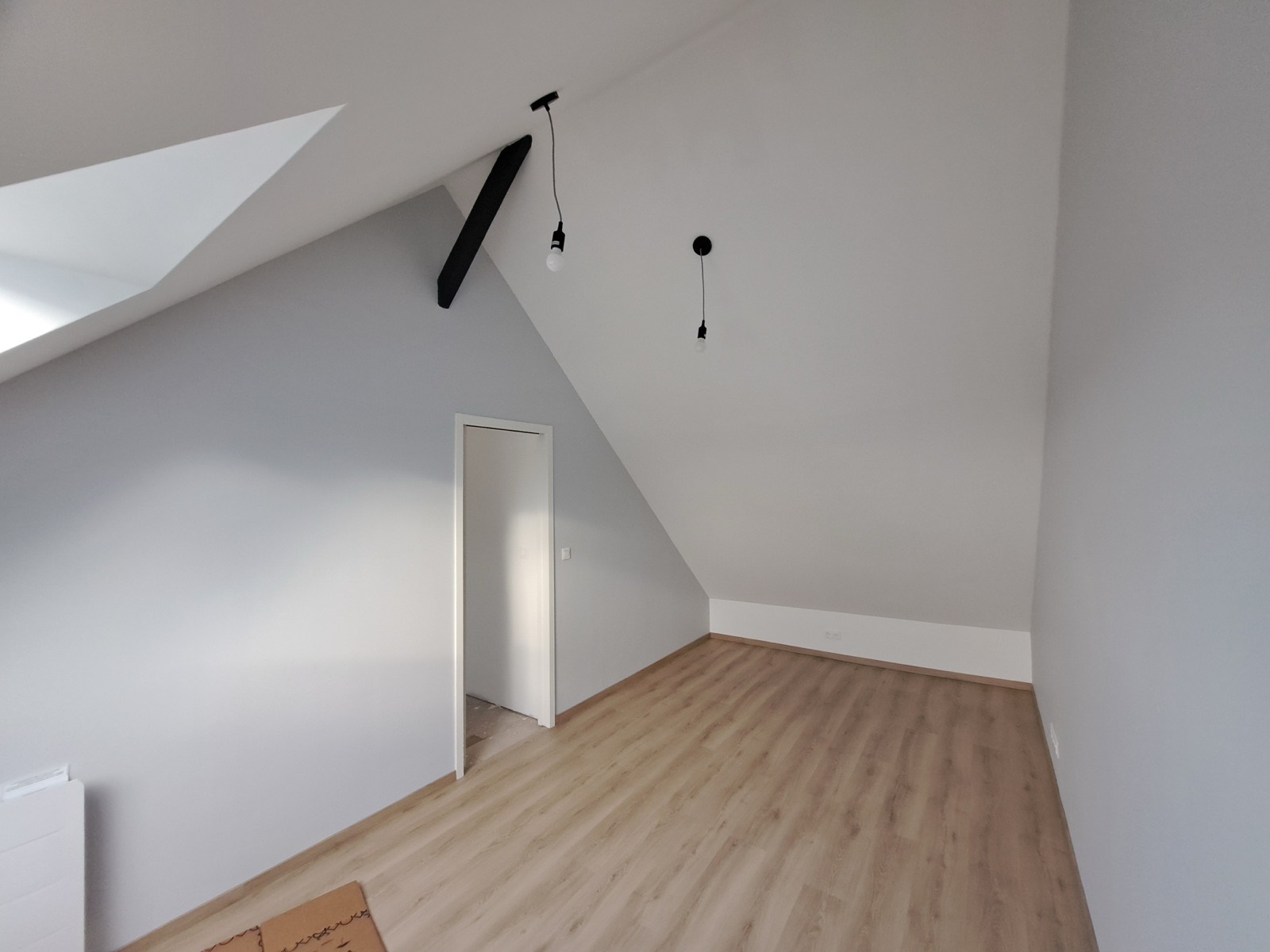 Chambre sous combles terminée avec parquet clair et velux, finitions soignées Dagicour